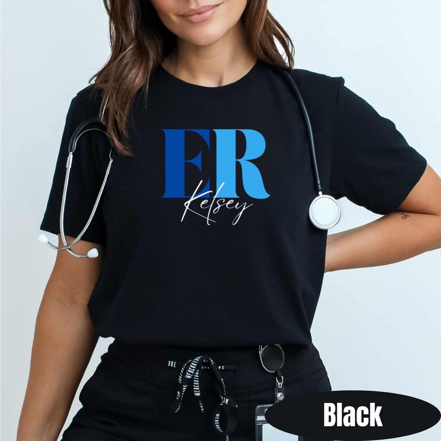 A nurse in a clinical setting wearing the custom ER script tee in black wearing a stethoscope.